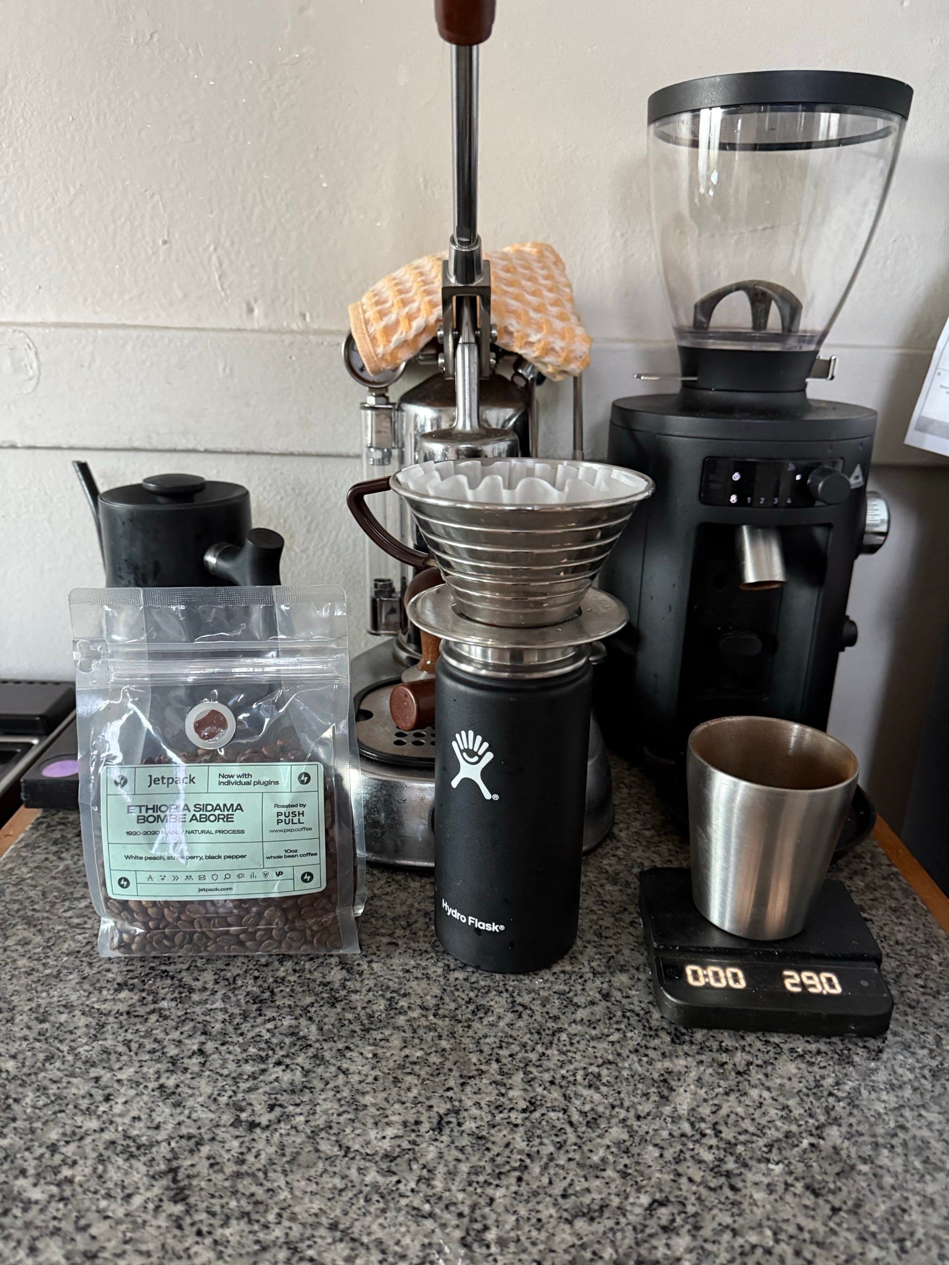 A pourover station — dripper, scale, grinder, and beans on a kitchen counter